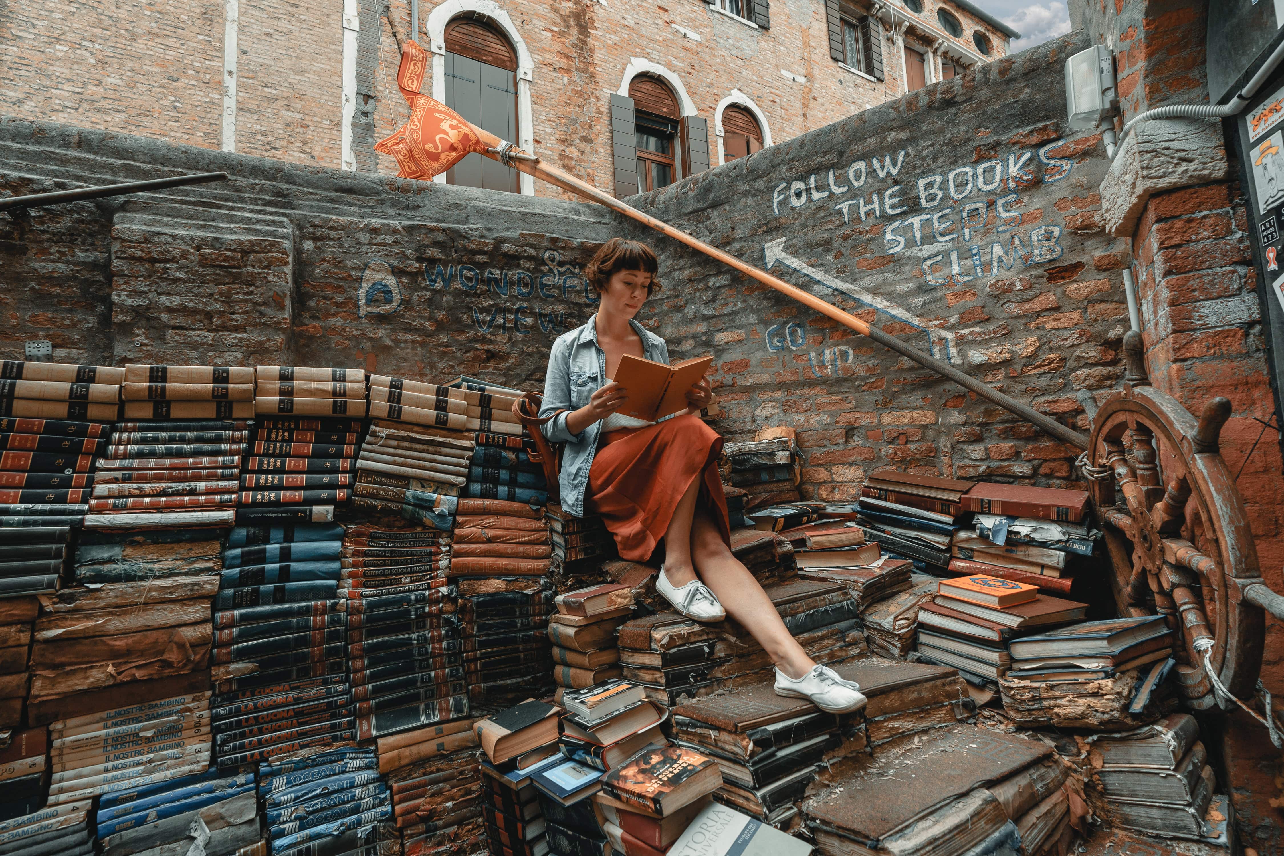 Girl reading books on stairs surrounded by Spanish books free