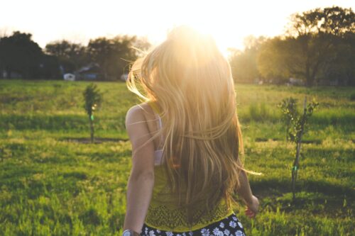 girl facing into sunshine in field